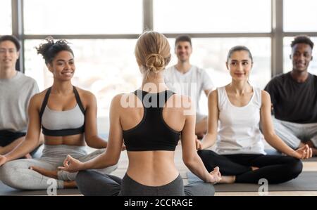 Groupe multiculturel d'homme et de femme pratiquant le yoga avec instructeur en studio Banque D'Images