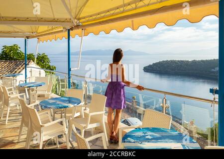 Une jeune fille bénéficiant d'une vue depuis une taverne en bord de mer dans le village de Spartochori, Meganissi, Iles Ioniennes, Grèce Banque D'Images