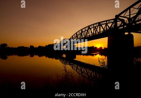 Pont ferroviaire près de Barby au coucher du soleil se reflétant dans la rivière Elbe. Banque D'Images