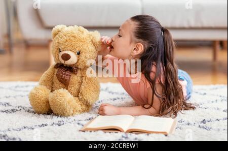 Asian Kid Girl partage secret avec Teddy Bear à la maison Banque D'Images