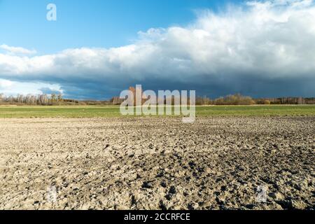 Champ labouré et nuage pluvieux, vue sur une journée ensoleillée de printemps Banque D'Images