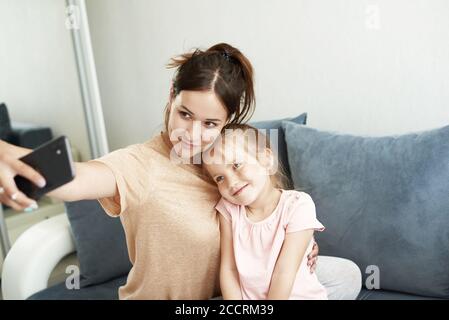 Une jeune femme attirante et sa petite fille mignonne prennent un selfie et un câlin. Banque D'Images