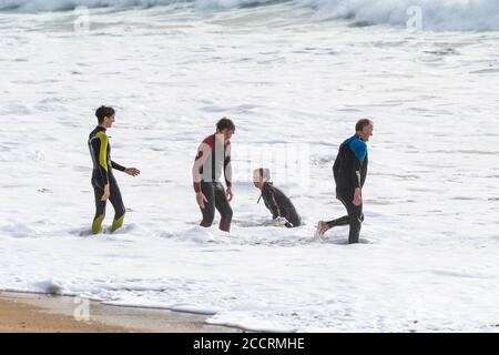 Vacanciers en combinaisons s'appréciant dans le surf sur la plage de Fistral à Newquay en Cornouailles. Banque D'Images