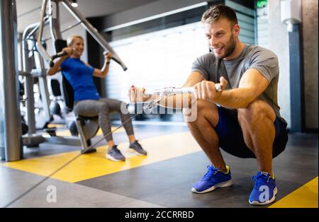 Portrait de la forme beau homme entraînement sur un appareil de fitness à la salle de gym Banque D'Images