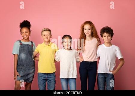 Concept de retour à l'école. Joyeux divers garçons et filles posant sur fond rose Banque D'Images