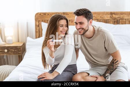 Surprise et futurs parents. L'homme et la femme heureux regardent le test de grossesse positif Banque D'Images