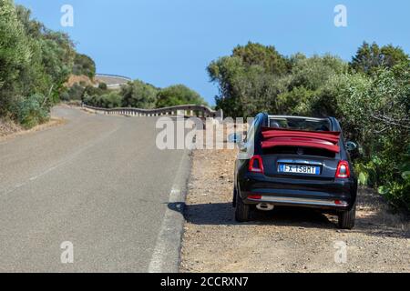 Sant'Antioco, Italie - 07 18 2020: Route côtière dans le sud de la Sardaigne en été avec une Fiat 500 cabriolet en premier plan. Banque D'Images