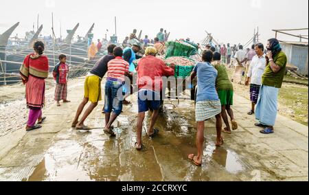 Chittagong, Bangladesh, le 23 décembre 2017 : les pêcheurs poussent une charrette chargée de nouvelles prises de crevettes dans un port de Chittagong, au Bangladesh Banque D'Images