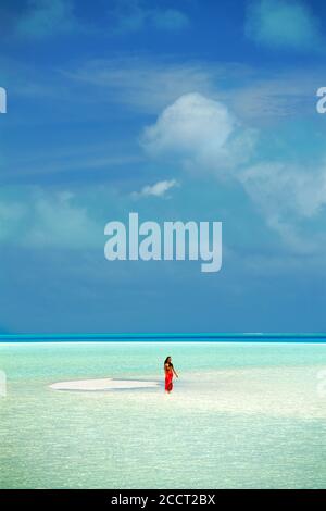 Femme portant du sarong rouge marchant sur un banc de sable dans le lagon d'Aitutaki dans les îles Cook. Pacifique Sud Banque D'Images