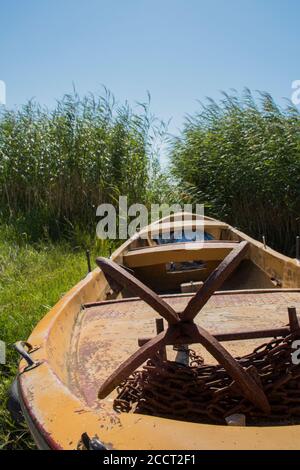 ancrage rouillé et chaîne rouillée sur le petit bateau photographié de près près près des roseaux verts. Banque D'Images