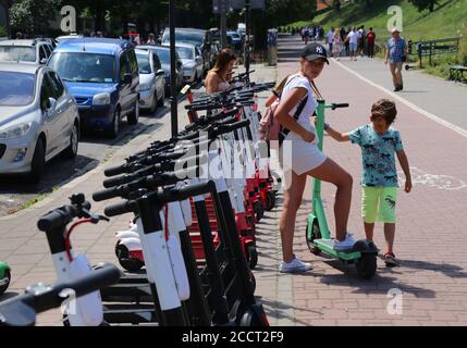 Cracovie. Cracovie. Pologne. Location de scooters électriques dans la rangée du centre de la vieille ville. Jeune femme avec enfant prenant le scooter. Banque D'Images