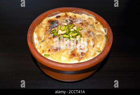 Arabe traditionnel, dessert oriental Om Ali. Vue de dessus. Pain égyptien Pudding dans un bol brun sur une table en bois sombre, gros plan. Pâtisserie égyptienne au four Banque D'Images