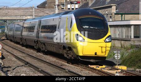 Avanti pendolino Electric train, West Coast main Line, Carnforth avec une décoration spéciale de masque et de message de couleur jaune les voyages sûrs portent une couverture de visage. Banque D'Images