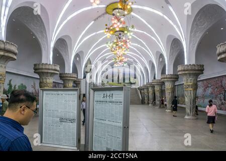 Un banlieue lit un journal sur une plate-forme d'une station de métro du Pyongyang, en Corée du Nord Banque D'Images