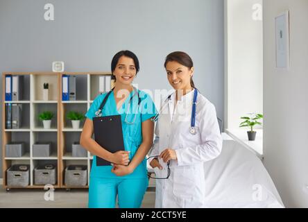Jeune médecin souriant et infirmière regardant la caméra en médecine clinique Banque D'Images