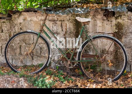 une vieille moto classique classique ancienne, vieille, abandonnée, rouillée ou corrodée, qui se penche contre un mur sur l'île grecque de zakynthos. Banque D'Images