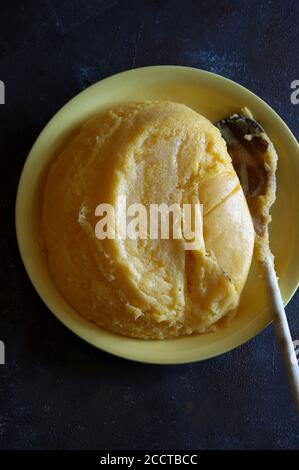 Polenta avec beurre et parmesan dans une assiette. Arrière-plan sombre. Vue de dessus. Copier l'espace Banque D'Images