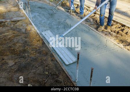 travailleur plâtrant le ciment de béton pendant l'entrepreneur de construction en utilisant un flotteur sur le trottoir Banque D'Images