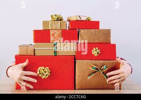 Personne palissade rouge boîtes de couleur froide Noël cadeaux. Garde les mains derrière une grosse pile de cadeaux. Banque D'Images