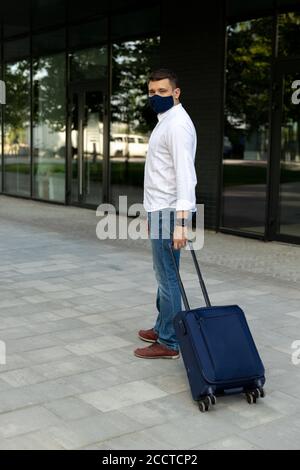 Homme dans des vêtements décontractés marchant avec une valise Banque D'Images