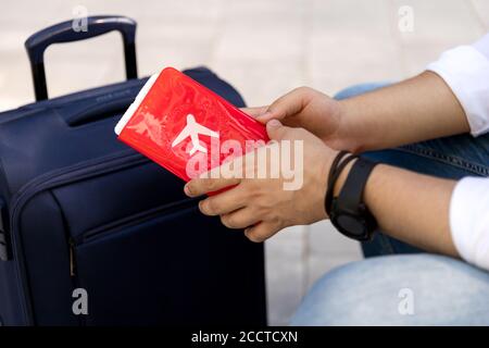 Homme dans des vêtements décontractés assis sur un banc avec un valise Banque D'Images