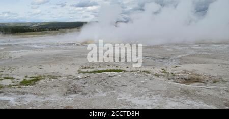 Fin du printemps dans le parc national de Yellowstone: Le geyser de clopsydra éclate avec le calme spasme Geyser dans le parc forestier dans le groupe de fontaines du bassin inférieur de Geyser Banque D'Images