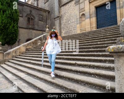 Femme mature et élégante pose sur les marches de la cathédrale de Baeza, Jaen, Espagne avec masque et parapluie transparent Banque D'Images