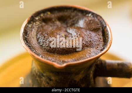 Café naturel avec mousse épaisse, brassé dans une cève de cuivre de la manière classique, sur un fond de bois, photo macro. Banque D'Images