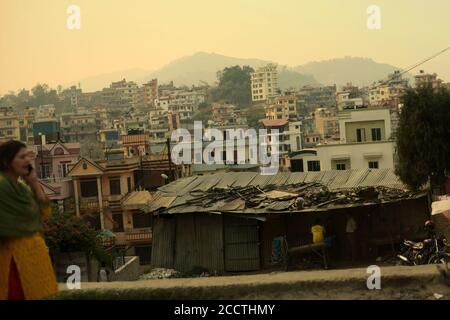 Un citoyen de Katmandou marchant sur le bord de la route, avec des logements résidentiels en arrière-plan, vu d'une route menant à Dhulikhel, Bagmati Pradesh, Népal. Banque D'Images