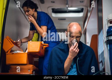 Un paramédic préparant un tube tombant, un homme sauvé d'un accident au premier plan. Banque D'Images