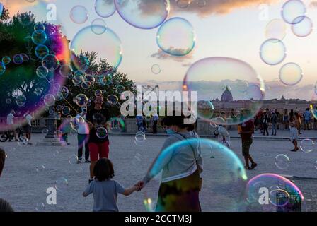 Rome, Italie, le 24 août 2020. Les gens prennent des photos et posent pour des photos contre un nuage de bulles de savon créé par un interprète de rue au Pincio à Villa Borghese, Rome, une terrasse populaire avec une vue sur le dôme de Saint Peters et le coucher de soleil sur la ville Credit: Stephen Bisgrove/Alay Live News Banque D'Images