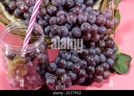 Pot avec grains et grappes de raisin. Jus de raisin. Boisson rafraîchissante. Boisson aux fruits. Ingrédients pour vins et jus. Fruits frais. Raisin rose. Banque D'Images