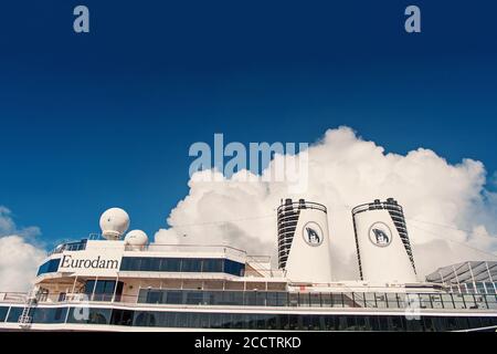 Miami, États-Unis - 31 décembre 2015 : ponts supérieurs et entonnoirs doubles d'Eurodam. Façade du bateau de croisière sur ciel bleu nuageux. Rangées de fenêtres et de balcons. Transport maritime. Aventure et découverte. Banque D'Images