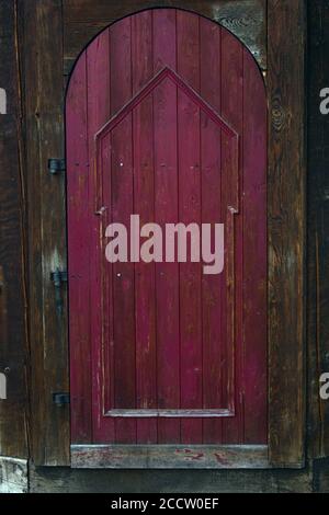 Une ancienne porte en bois rouge qui est également voûtée Banque D'Images