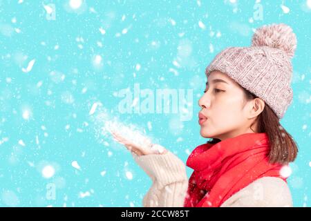 Jeune femme en vêtements d'hiver et neige soufflantes Banque D'Images