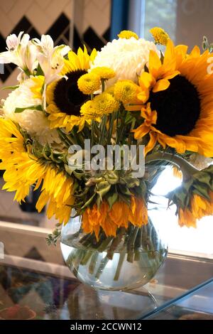 Gros plan bouquet d'une variété de fleurs avec de grands tournesols disposés dans un vase rond en verre transparent. St Paul Minnesota MN États-Unis Banque D'Images