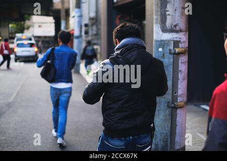 Homme marchant dans la rue en utilisant un smartphone et concept de distanciation sociale de derrière Banque D'Images