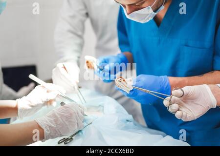 Groupe d'exploitation au travail des chirurgiens en chirurgie, dans le théâtre. L'équipe de médecine de réanimation portant des masques de protection en acier outils médicaux holding Banque D'Images