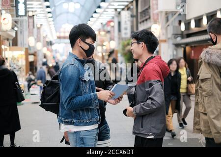 Groupe de jeunes amis asiatiques cessent de parler de ce voyage pour se déplacer dans la rue à pied pendant les heures de pointe Banque D'Images