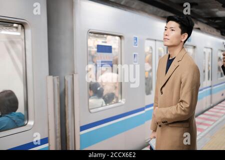 Portrait du jeune homme asiatique attendant le train et aller à la station suivante Banque D'Images