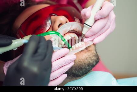 Le nettoyage des dents professionnel. Dentiste nettoie les dents d'un patient de sexe masculin. Banque D'Images