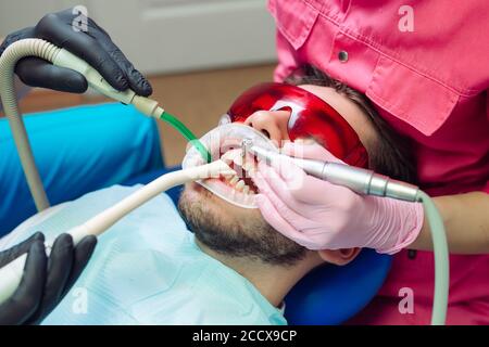 Le nettoyage des dents professionnel. Dentiste nettoie les dents d'un patient de sexe masculin. Banque D'Images