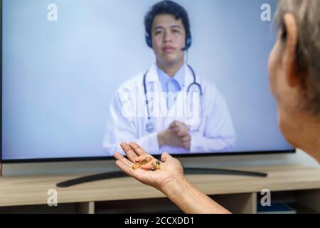 Femme âgée s'assoit à la maison après avoir consulté un médecin en ligne Banque D'Images