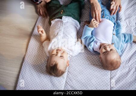 Deux adorables frères jumeaux bébé enfant bébé tout-petit caressé les parents sont couchés sur un tapis blanc Banque D'Images