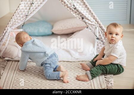 Couple de petits garçons de 1 an jouant seuls dans une tente jouet avec guirlande à la garderie à l'intérieur de la maison. Banque D'Images