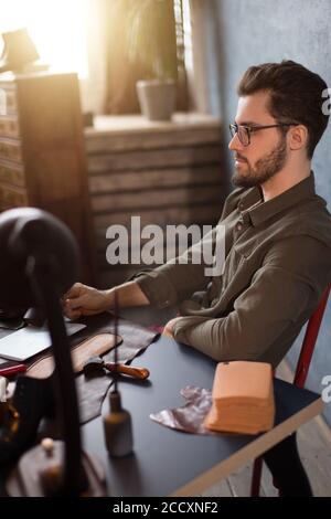 Créateur de chaussures ayant un reste en position assise au travail. close up side view photo. Banque D'Images