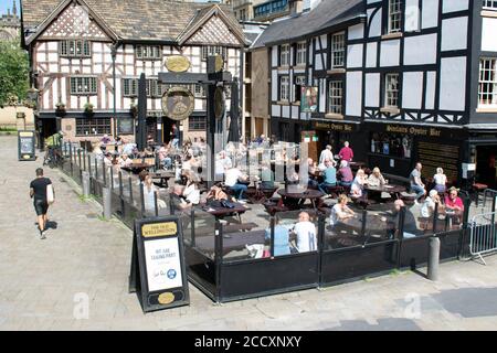 Manger dehors pour aider à la mise en place. Foule à l'extérieur du bar Sinclairs Oyster. Tableau sandwich avec publicité pour la participation au programme. Manchester Royaume-Uni. Banque D'Images