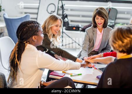 Les jeunes femmes créatives pigistes multiraciale en réunion de bureau moderne. Femme elebrate avec succès une équipe de création réussie saut dans la croissance des ventes Banque D'Images