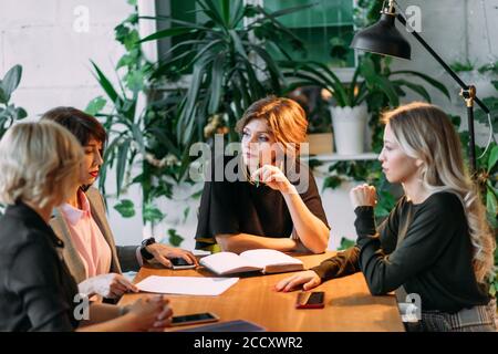 Groupe d'younghardworking les jeunes femmes travailler tard le soir dans la salle de réunion d'essayer de remplir leurs missions. Banque D'Images