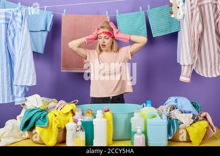 une femme émotif choquée achète beaucoup de vêtements sales. isolé fond bleu. femme désespérée surpris de la qualité des détergents. isolé blu Banque D'Images